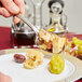 A person holding a Libbey stainless steel serving spoon over a plate of food.