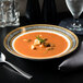 A 10 Strawberry Street Elegance porcelain rim soup bowl with a spoon of soup on a table.