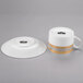 A white porcelain coffee cup and saucer with gold accents.