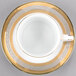 A white porcelain teacup and saucer with gold trim.