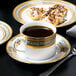 A table with 10 Strawberry Street Elegance porcelain saucers and cups of coffee.
