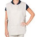 A woman wearing an ivory Intedge cobbler apron with black pants.