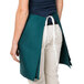 A woman wearing a Hunter Green Intedge waist apron with white ties.