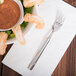 A bowl of shrimp and sauce with a Libbey Zephyr cocktail fork on a napkin.