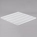 A white coated wire shelf grid on a gray surface.