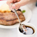 A person holding a Libbey Geneva European teaspoon over a cup of coffee.