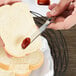 A person cutting a piece of bread with a Libbey Geneva stainless steel bread and butter knife.