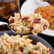 A close-up of a Libbey Madison stainless steel serving spoon full of pasta with meat and cheese.