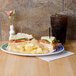 A white oval melamine platter with a sandwich and chips.