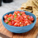 A Libbey blueberry porcelain salsa bowl filled with salsa and chips.