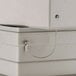 A metal cable attached to a white Commercial Zone waste container security box.