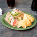 A Libbey sage carved oval porcelain platter with a sandwich and chips on it on a table.