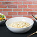 A group of Tablecraft Sierra melamine bowls filled with macaroni salad, salad, and fruit.