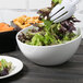 A Tablecraft Sierra white melamine bowl filled with salad on a table.