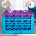 A woman in a white coat placing glasses in a lavender Carlisle glass rack.