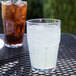 A clear Bahama plastic tumbler filled with ice and a drink on a table.