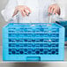 A woman pouring glasses into a blue Carlisle glass rack with honeycombs.