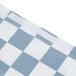 A close-up of a blue and white checkered plastic bag with a Creative Converting Stay Put Black Check tablecloth inside.