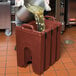 A man pouring liquid into a Cambro soup carrier.