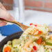 A hand holding a Fineline Gold Look serving fork with pasta.