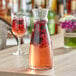 An Arcoroc glass carafe filled with wine and berries on a table.