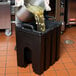 A man pouring liquid into a black Cambro soup carrier.