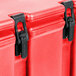 A red plastic Cambro insulated soup carrier with black metal and plastic latches.