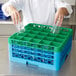 A chef putting glasses into a green Carlisle OptiClean glass rack.