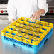 A woman pouring water from a bottle into a yellow Carlisle glass rack.