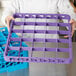 A person holding a purple Carlisle OptiClean glass rack extender tray.