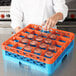 A woman pouring water into an orange Carlisle glass rack with an extender.