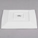 A white square Tuxton Pacifica china plate with black text.
