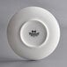 A bright white Tuxton saucer with an embossed logo in black.