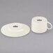 A white cup and saucer with a Royal Cream pattern on the edge.