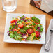 A table set with a pack of 6 Acopa square white porcelain plates filled with salad.