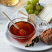 A plate of cheese, grapes, and Monarch's Choice Orange Blossom Honey on a table.