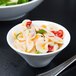 A Libbey white porcelain bowl filled with pasta and vegetables on a table.