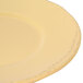 A close-up of a Libbey round yellow porcelain plate with a wide rim.