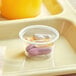 A white plastic souffle cup with pills in it.