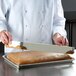 A chef uses a MFG Tray fiberglass sheet pan extender to cut cake.