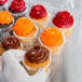 A person holding a Polar Pak clear plastic cupcake container with 12 cupcakes inside.