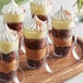 A glass cup with a layer of chocolate and whipped cream using a Visions clear plastic spoon.