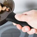 A hand holding a black Lodge handle over a pan of food.