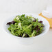 An American Metalcraft white melamine serving bowl filled with lettuce leaves and a fork.