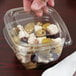 A hand holding a Sabert clear plastic bowl filled with olives.