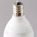 A close-up of a Satco clear warm white LED light bulb with a candelabra base.