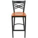 A Lancaster Table & Seating black cross back bar stool with a cherry wood seat.