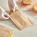 A person putting a cookie in a Choice brown paper bag.