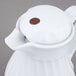 a white pitcher with a brown button