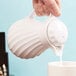 A person pouring milk into a white Vollrath SwirlServe beverage server.